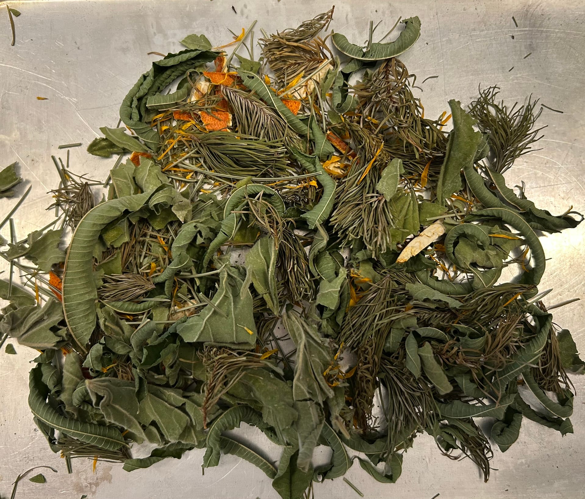 Photo of green and orange dried plants coming together on a countertop to become tea