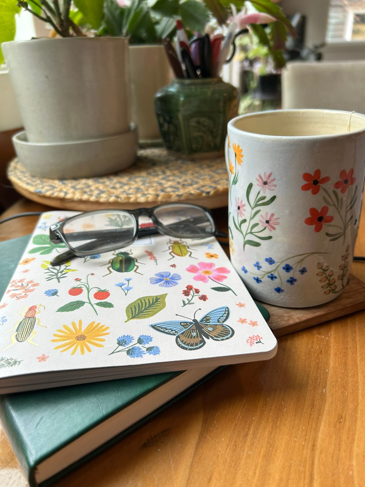Picture of my notebooks, planters, and a mug covered with colorful flowers, leaves, butterflies. Gifts from friends.