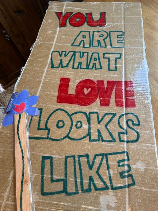 Photo of a cardboard sign with handwritten words that say, "You are what love looks like."